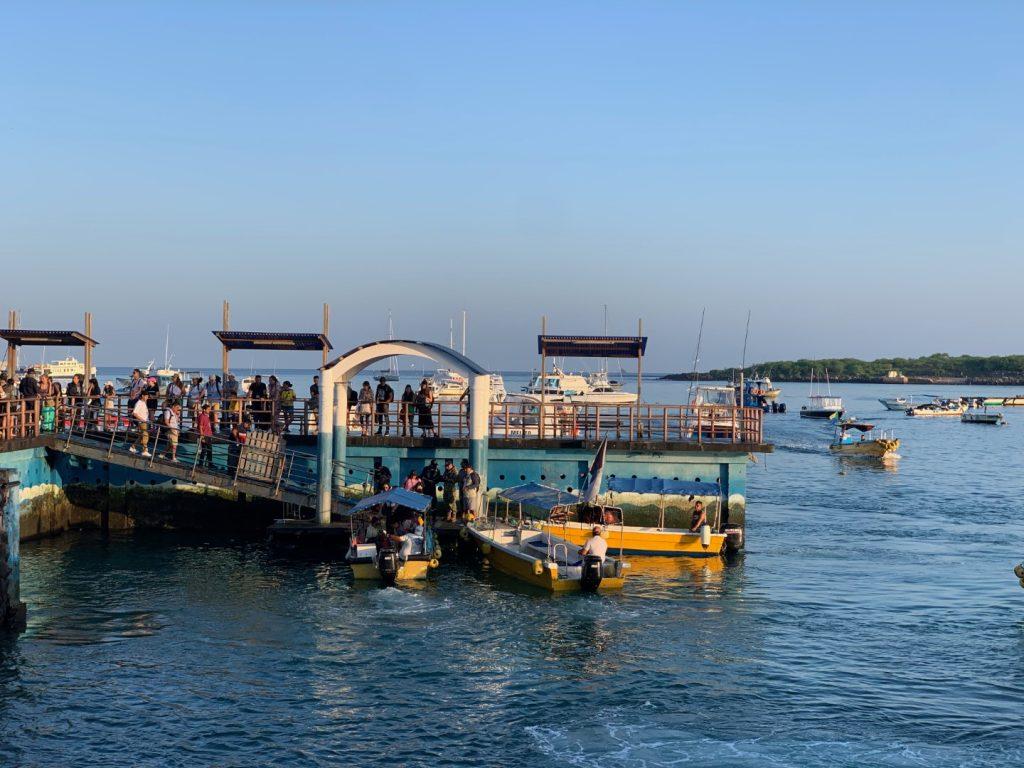 Tourists lining up on the dock to catch the water taxis to their small cruise boats (Isabela Island, Galapagos)